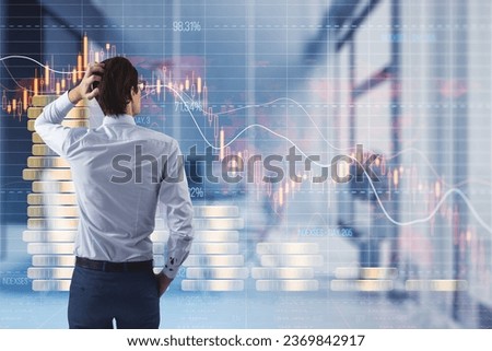 Back view of thoughtful man looking at creative forex chart hologram with declining stacked coins on blurry office interior background. Financial recession, plummet concept. Double exposure