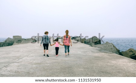 Back view of women walking by sea pier