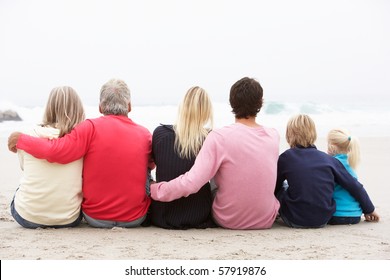 Back View Of Three Generation Family Sitting On Winter Beach Together