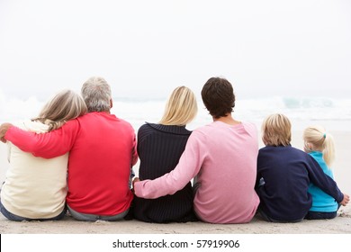 Back View Of Three Generation Family Sitting On Winter Beach Together