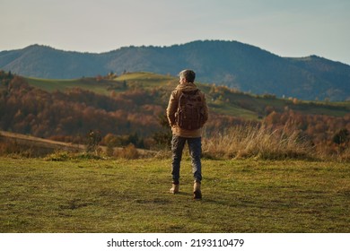 Back view tourist adventurous man with backpack stands on mountain meadow and enjoys inspiring epic landscape over mountains - Powered by Shutterstock