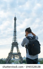 Back view of tourist with backpack taking picture of Eiffel tower.