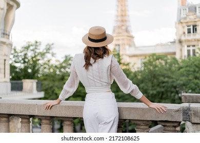 Back view of tourist in sun hat standing with blurred Eiffel tower at background in Paris - Powered by Shutterstock