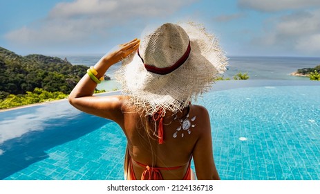 Back view  tourist woman Suntan lotion applying sunscreen solar cream on the poolside and looking view with seashore 