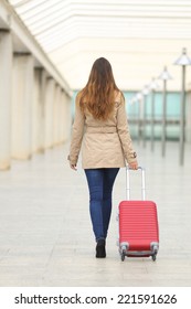 Back View Of A Tourist Woman Walking And Carrying A Suit Case In An Airport Or Station