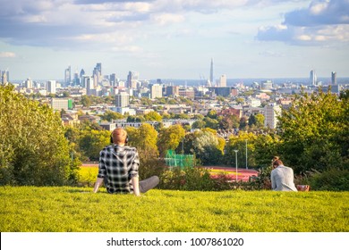 Back view of tourists looking over London city skyline from Parliament Hill in Hampstead Heath