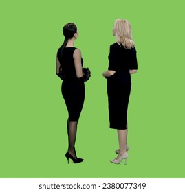 Back view two adult women in black dresses standing and watching at something on green background, Chroma key - Powered by Shutterstock