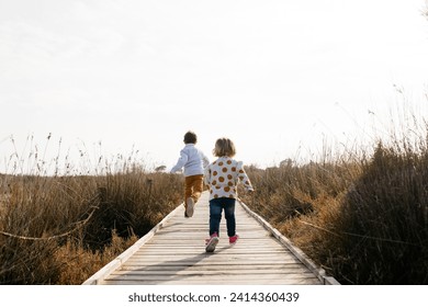 Back view of two little children running on boardwalk - Powered by Shutterstock