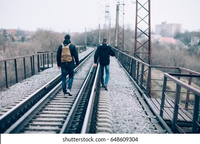 Back View Of Two Men Walking Away On The Railroad Tracks