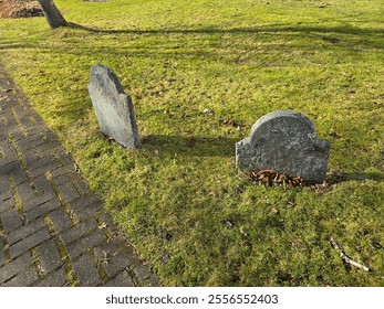 A back view of two old grave stones in the grass.