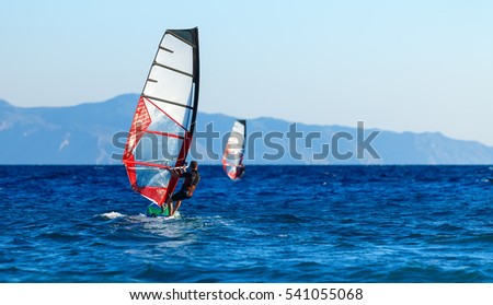Back view of two windsurfers in action mooving parallel