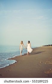 Back view of two woman on holiday travel vacation beach. Sunny ocean sky background