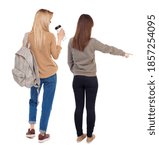 Back view of two young woman photographed on a mobile phone in sweater. Rear view people collection. backside view of person. Rear view. Isolated over white background.