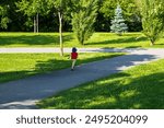 Back view of unattended small child running away in park alley during a summer afternoon, Montreal, Quebec, Canada 