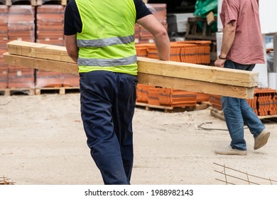 Back View Of Unknown Man Construction Worker Holding And Carry Lumber At Warehouse Or Construction Site