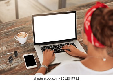 Back view of unrecognizable female model advertizes news and keyboards on laptop computer with balnk copy screen for your advertising content. Woman`s hands types information on internet websites - Powered by Shutterstock