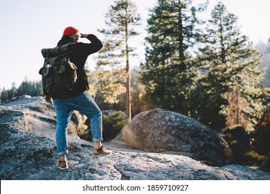 Back View Of Unrecognizable Male Traveler In Casual Clothes And Hat With Backpack Standing On Rock And Looking Away At Sunset In Yosemite National Park