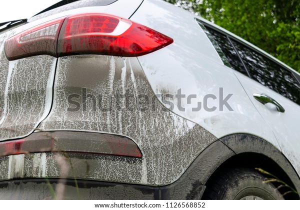Back view of a very dirty car.\
Fragment of a dirty SUV. Dirty headlights, wheel and bumper of the\
off-road car with swamp splashes on a side\
panel