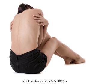 Back View Of Very Thin Girl With Her Arms Wrapped About Her Torso, Isolated On White