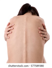 Back view of very thin girl with her arms wrapped about her torso, isolated on white
