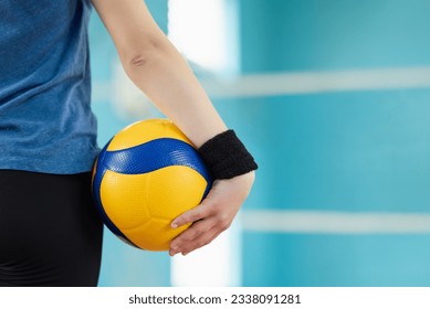 Back view of volleyball ball in hand of a female player standing in gym, close up. Training, volleyball game, mastering skills concept - Powered by Shutterstock