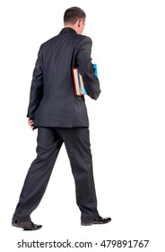 Back View Of Walking  Business Man With Books. Going Young Guy In Black Suit. Isolated Over White Background. Rear View People Collection. Backside View Of Person