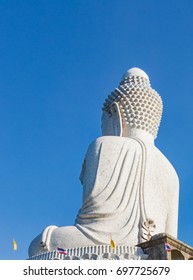 Back view of the white marble statue of Big Buddha on blue sky background.