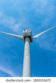 Back view of a windmill tower against a clear blue sky background. Sustainable development, renewable energy. Wind turbine generated electricity. Selective focus.