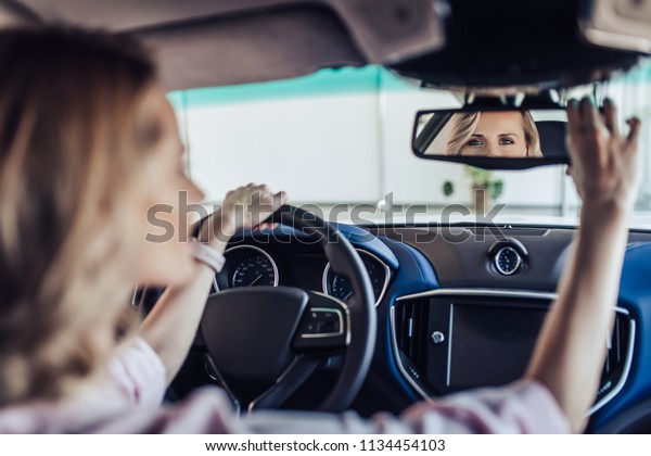 back\
view of woman adjusting the rear view mirror in\
car