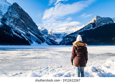 Back View Of A Woman Admiring The Frozen Lake Louise In Winter, Canada