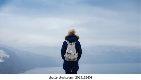 Back View Of Woman In Blue Jacket And Hat On Shore Of North Sea On Cold Winter Day. Mood Scandinavian Weather. Travel Adventure Lifestyle Idea And Concept