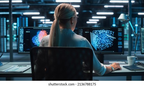 Back View of the Woman Computer Administrator and Scientist Create Neural Network at the Evening Office. Two Displays Showing 3D Representations of Neural Networks