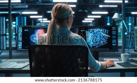 Back View of the Woman Computer Administrator and Scientist Create Neural Network at the Evening Office. Two Displays Showing 3D Representations of Neural Networks