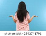 Back view of woman confusing. Young shocked woman with hands up. Isolated on blue background. Woman showing empty hands.