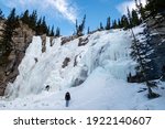 Back view of a woman facing the frozen Tangle Creek Falls in Jasper national park, Canada