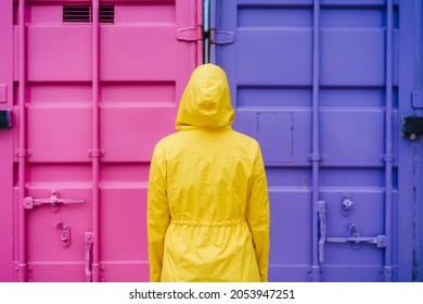 back view of woman with hood wearing yellow raincoat over pink and purple background. Colorful lifestyle Outdoors