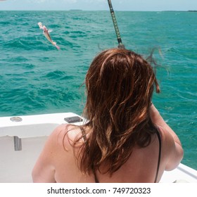 Back View Of Woman With Long Red Hair Catching Small Fish On Deep Sea Fishing Boat