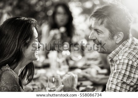 Back view,  woman  lunching with friends on a terrace table. Black and white
