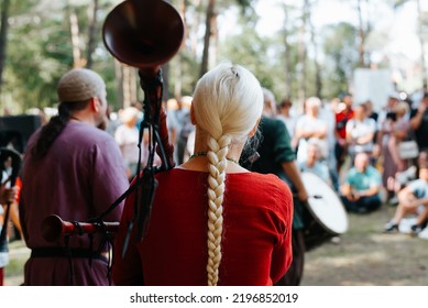 Back View Of A Woman Musician In A Medieval Costume Playing The Bagpipes At An Outdoor Folk Concert.