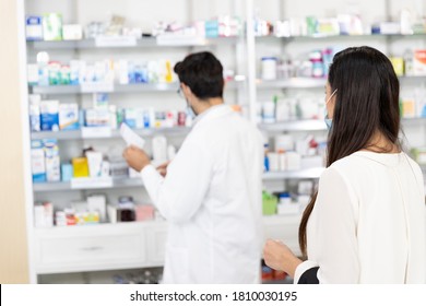 Back View Woman Patient And Male Pharmacist In Modern Pharmacy. Selling Medications To Prescription