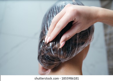 Back View. Woman Puts A Shower Cap On Her Hair