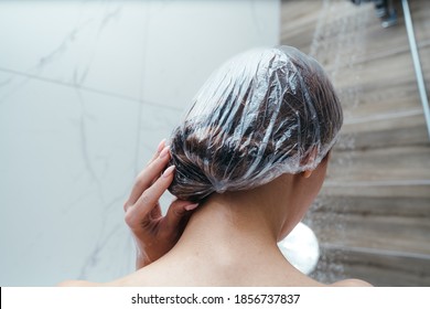 Back View. Woman Puts A Shower Cap On Her Hair