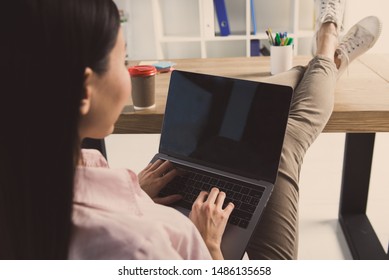 Back View Of Woman Resting At Work With Feet Up The Desk And Working With Laptop