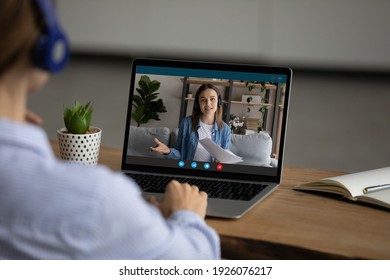 Back view of woman sit at desk at home office have webcam online meeting on computer with colleague. Female talk speak on video call with teacher tutor, engaged in web lesson. Virtual event concept. - Shutterstock ID 1926076217