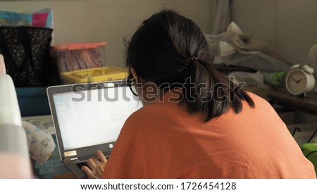 Back view woman sit and work with laptop in house.