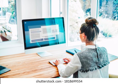 Back View Of Woman Sitting Behind Her Computer And Typing On Keyboard While Working. Businesswoman Working From Home. Home Office.