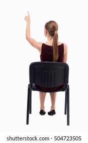 Back View Of Woman Sitting On Chair And Pointing.  Rear View People Collection.  Backside View Of Person.  Isolated Over White Background. A Girl In A Burgundy Dress Sitting On A Chair.