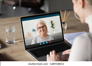 Back View Of Woman Speak Talk On Video Call On Computer With Smiling Elderly Mother, Young Female Communicate Online Using Laptop Webcam Chat With Happy Mature Mom, Quarantine At Home