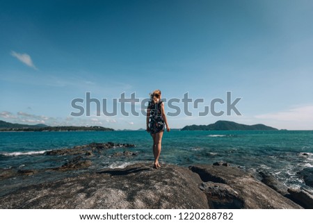Back view woman standing in front of the sea . Back view young girl on the rocks near the wild ocean