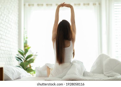 Back Of View Woman Stretching Her Arm After Wake Up On Bed And Looking Outside Windows In Bedroom Feeling So Fresh And Relax In The Morning,Healthcare Concept 